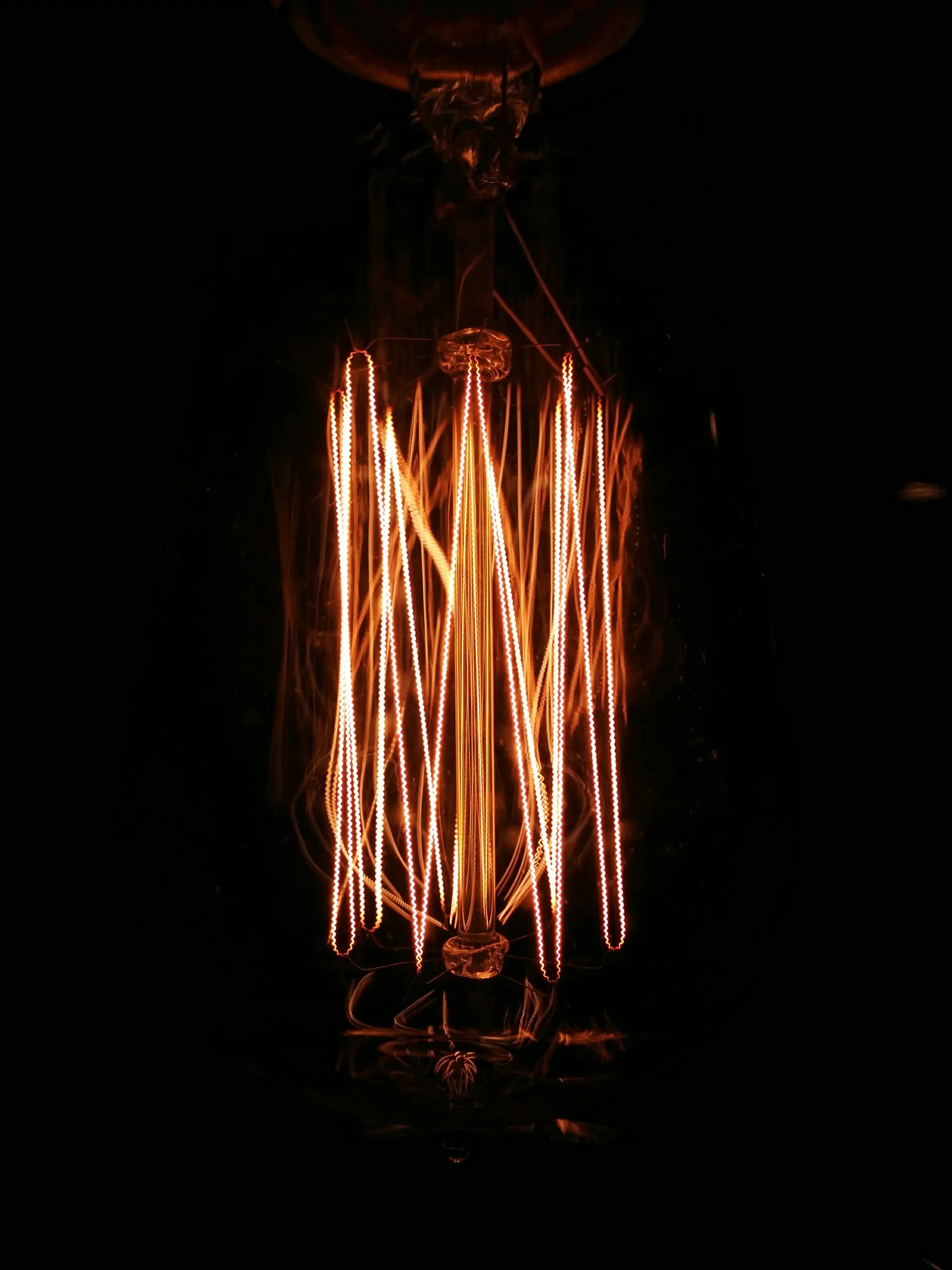 Filamento incandescente de una bombilla vintage brillando en naranja sobre fondo negro
