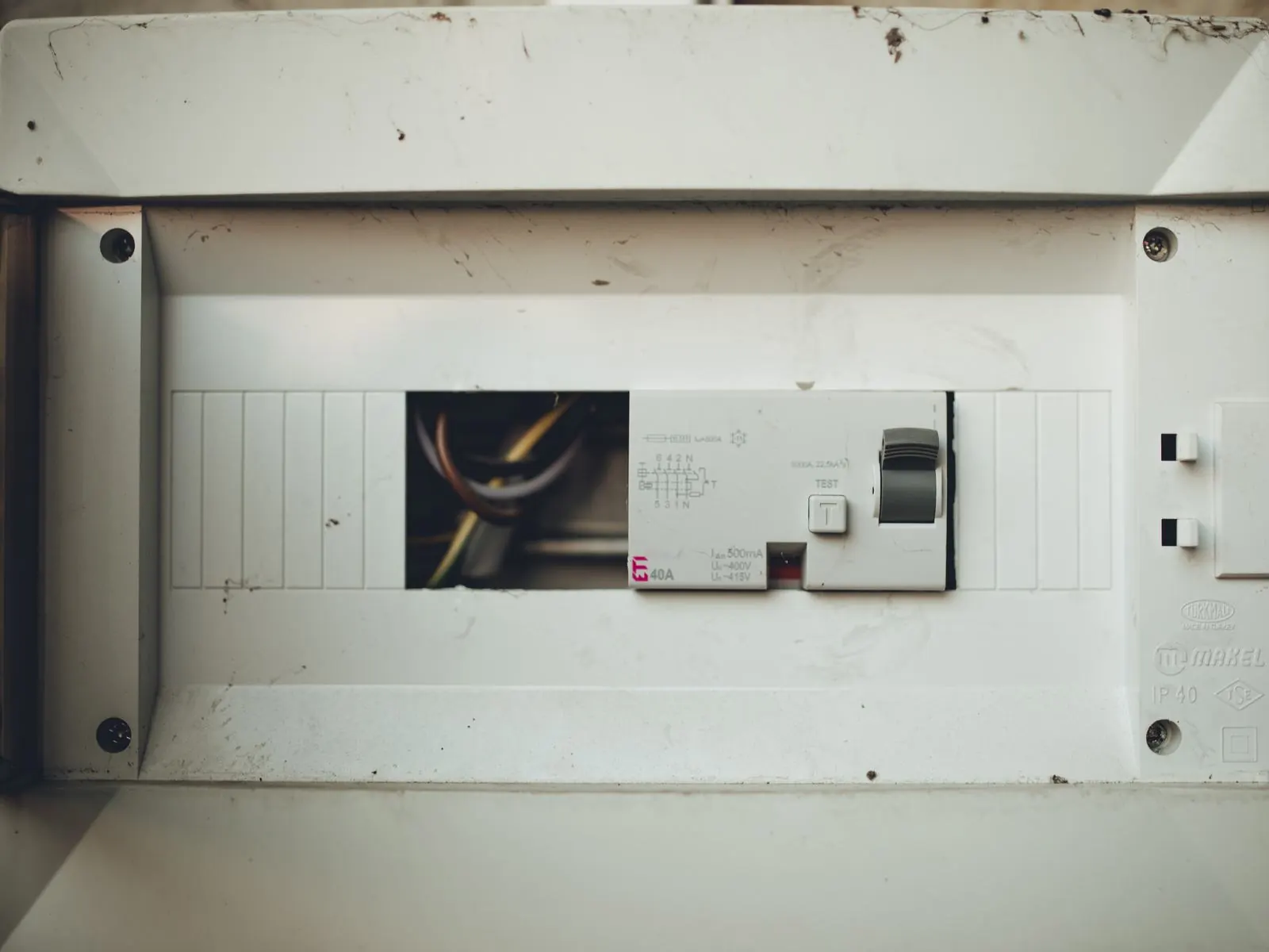 Cuadro eléctrico empotrado con la tapa abierta y un interruptor diferencial en el carril DIN