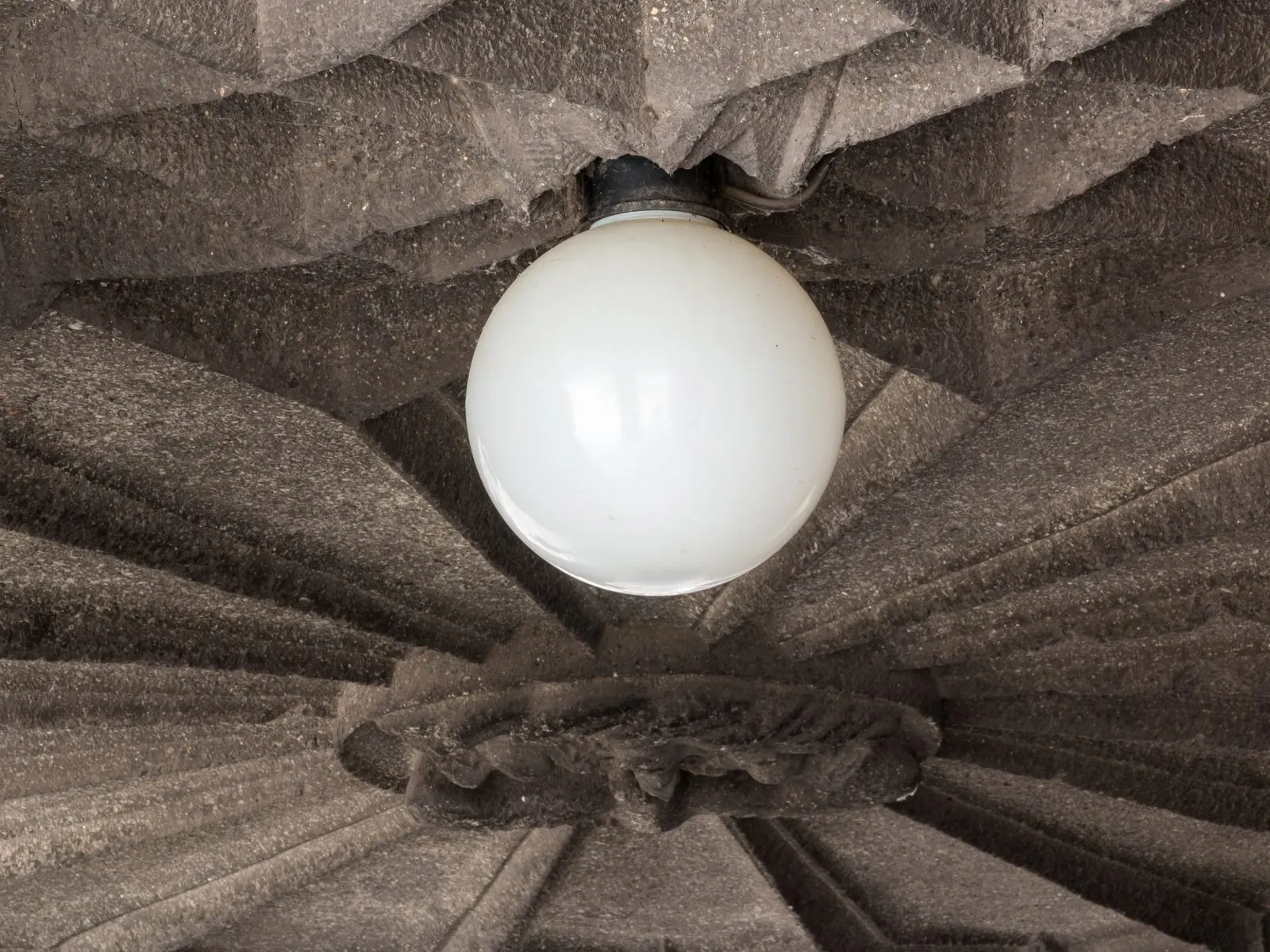 Plafón de globo blanco encendido en el centro de un techo con relieve